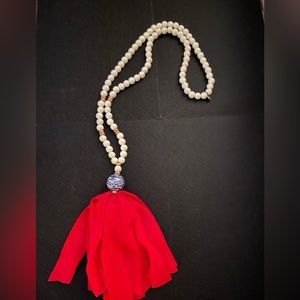 White beaded necklace with red ribbon